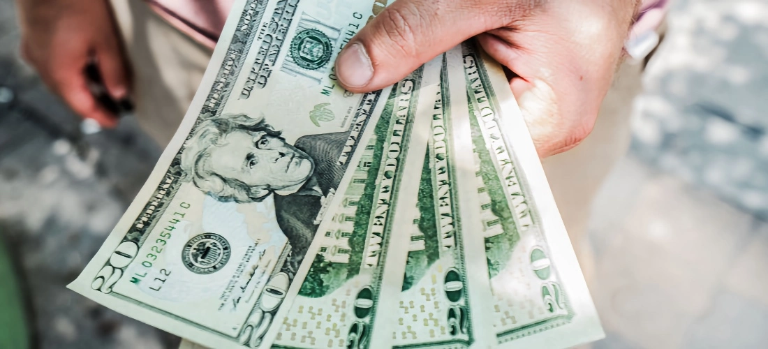 Image of man's hand holding US dollar bills